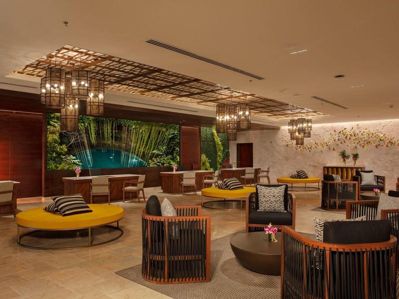 Area lounge dell'hotel moderna e aperta con sedute rotonde e illuminazione calda.