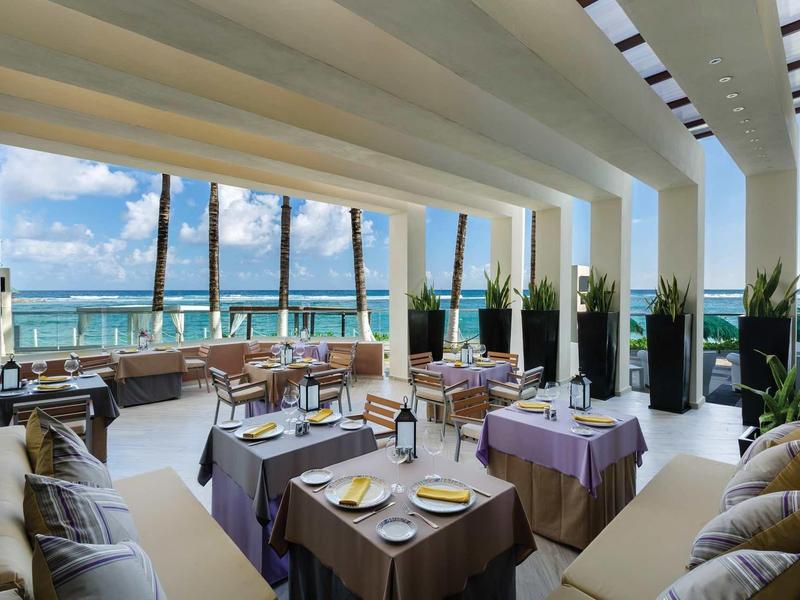 Ristorante elegante con vista sul mare, tavoli apparecchiati e architettura moderna.