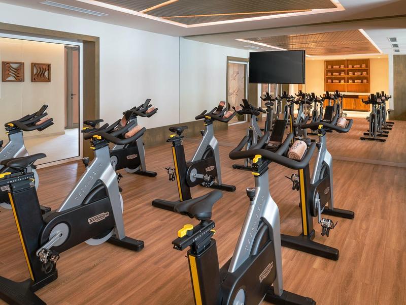 Gimnasio moderno con bicicletas estáticas y suelo de madera en un hotel.