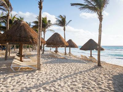 Palme, ombrelloni e sabbia sulla spiaggia al tramonto