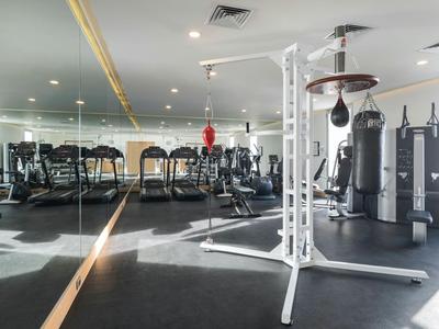 Světelná posilovna s moderním vybavením a zrcadlovou stěnou.