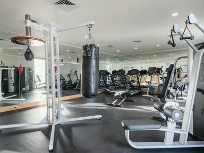 Moderní posilovna s boxovacím pytlem, zrcadlovou stěnou a různými posilovacími stroji.