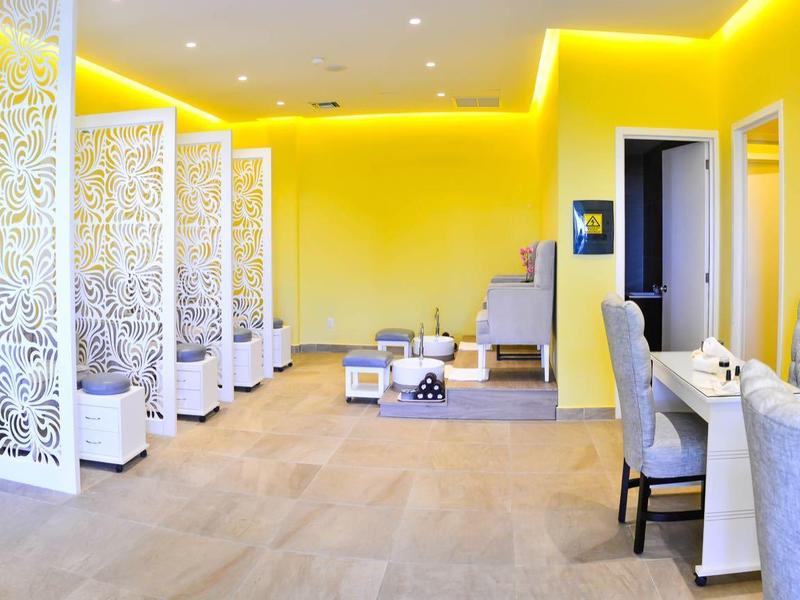 Area spa luminosa gialla con sedie bianche, divisori e atmosfera rilassante.