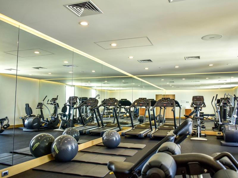 Palestra moderna con vari attrezzi da allenamento e grandi specchi alle pareti.