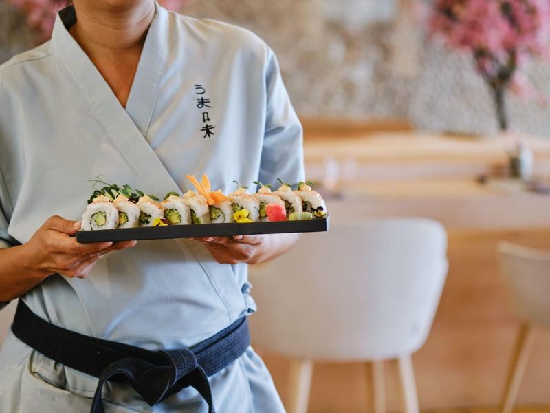 Personale di servizio che tiene un vassoio con sushi disposto in un ristorante.