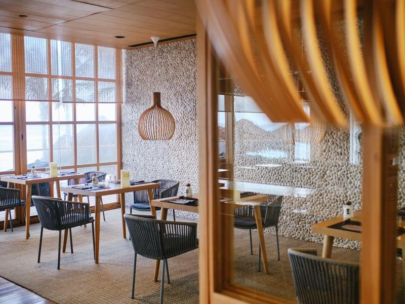 Ristorante luminoso con mobili in legno, grandi finestre e vista sulle montagne innevate.