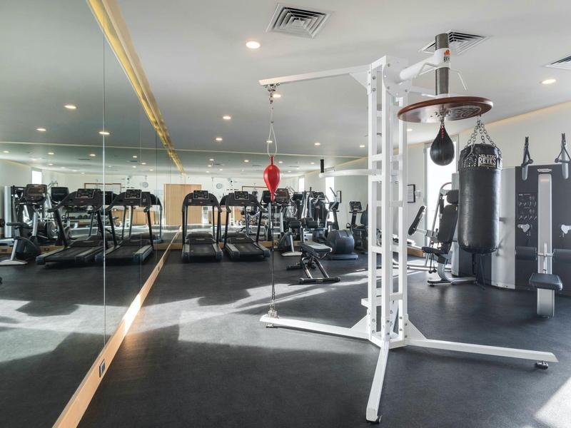 Palestra luminosa con varie attrezzature per l'allenamento e grandi specchi alla parete.