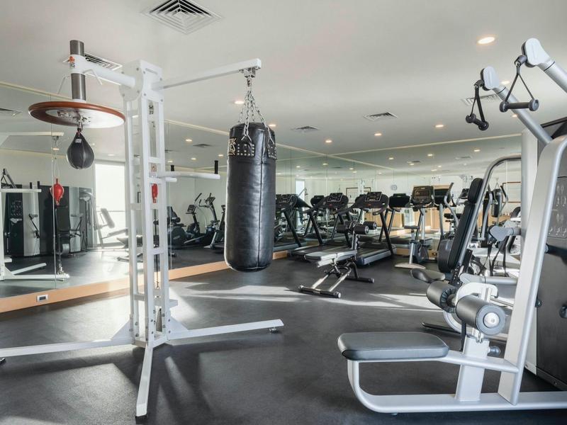Palestra luminosa con attrezzi per allenamento e sacco da boxe in un hotel moderno.