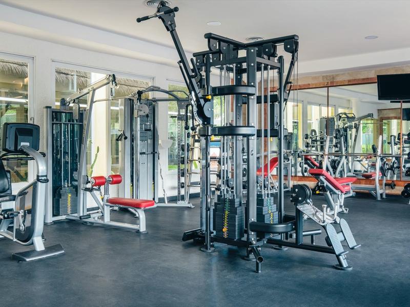 Gimnasio bien equipado con máquinas y espejos en un hotel.