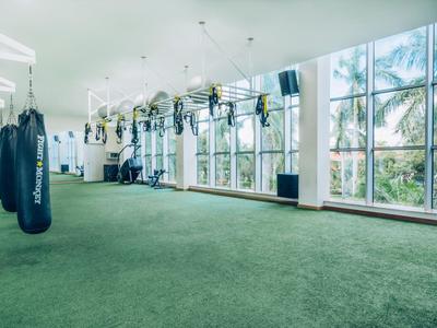 Großer, heller Trainingsraum mit grüner Teppichfläche und mehreren Hängesäcken an der Decke.