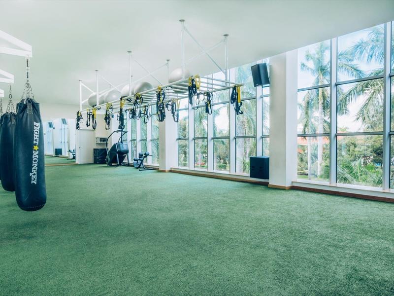 Ampia palestra con sacchi da boxe e grandi finestre con vista su palme