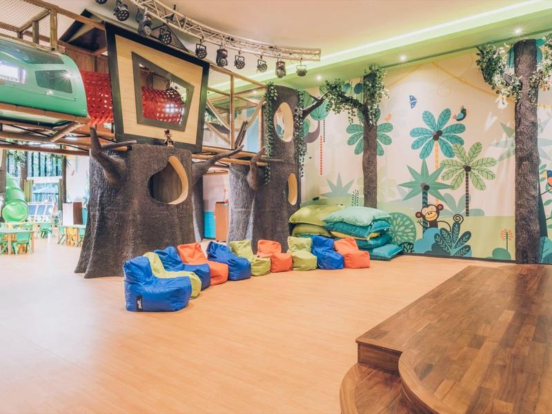 Area giochi colorata per bambini con decorazioni a casa sull'albero e pouf in un hotel.