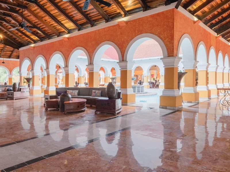 Ampia lounge dell'hotel con pareti rosse, finestre ad arco e pavimenti in marmo lucido.
