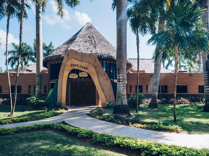 Ingresso di un hotel con palme e vegetazione tropicale alla luce del sole