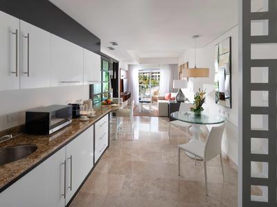 Cucina aperta moderna con mobili bianchi e vista sull'area pranzo e soggiorno.