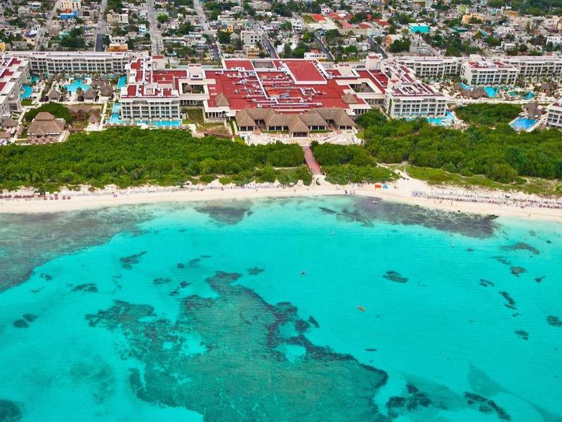 Vista aerea di un resort su una spiaggia di sabbia bianca con mare turchese trasparente.