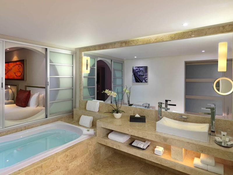 Bagno moderno con vasca idromassaggio, grandi specchi e illuminazione elegante.