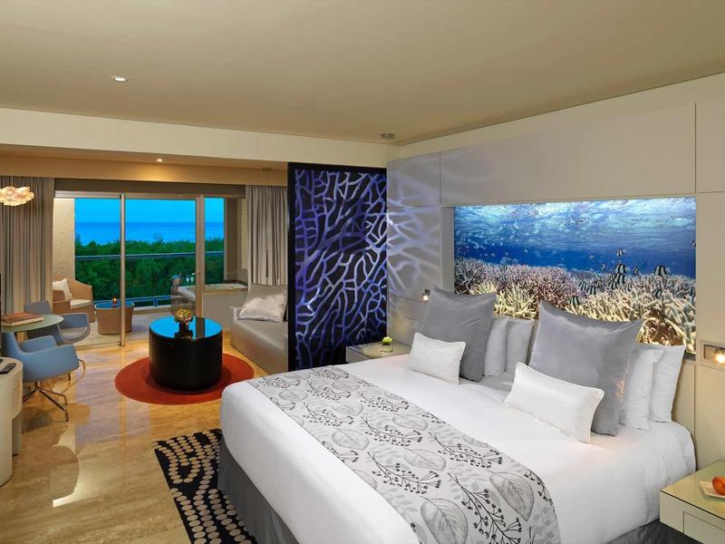 Camera d'hotel moderna con letto grande, TV e finestra panoramica con vista sulle montagne.