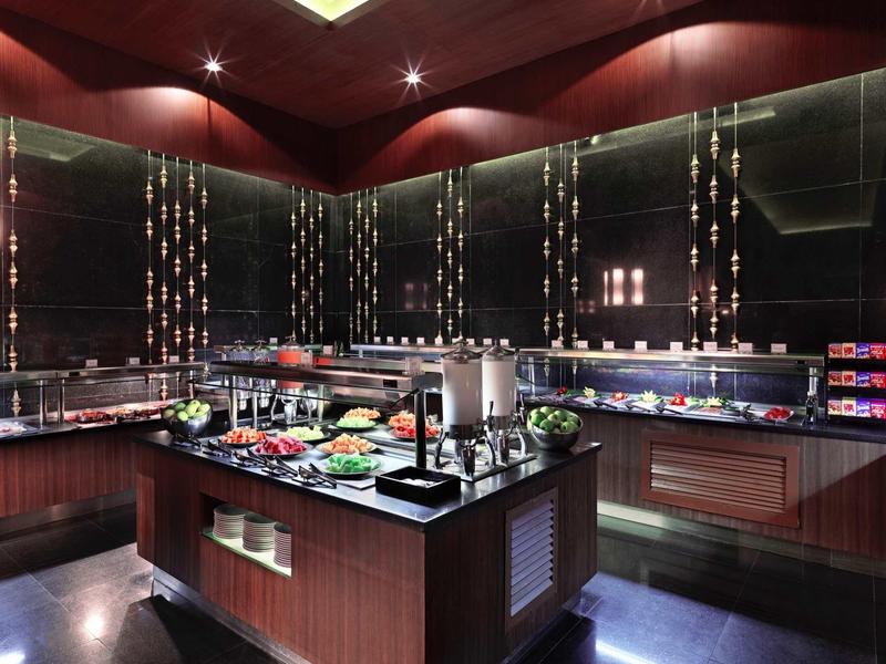 Sala da pranzo dell'hotel modernamente arredata con buffet e mobili in legno scuro.