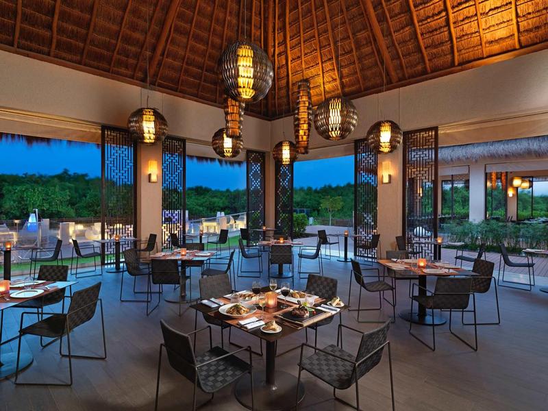 Ristorante elegante a concetto aperto con vista sul giardino al crepuscolo.