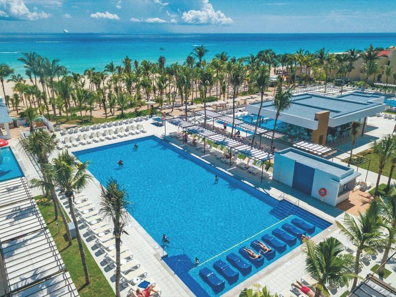 Large outdoor pool in a modern resort with palm trees and sea view.