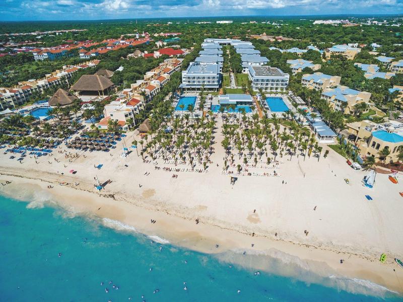 Aerial view of a resort with pools, sandy beach, and clear blue sea.
