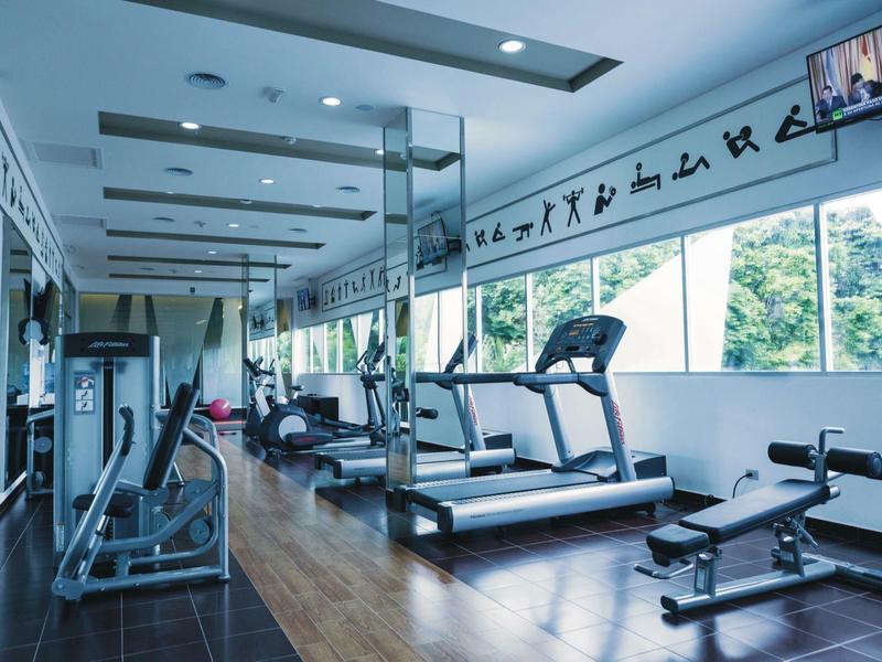 Modern gym with treadmills, weight benches, and panoramic windows with a view.