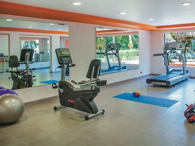 Moderner Fitnessraum mit Laufband, Fahrrad, Spiegelwand und bunten Trainingsbällen.