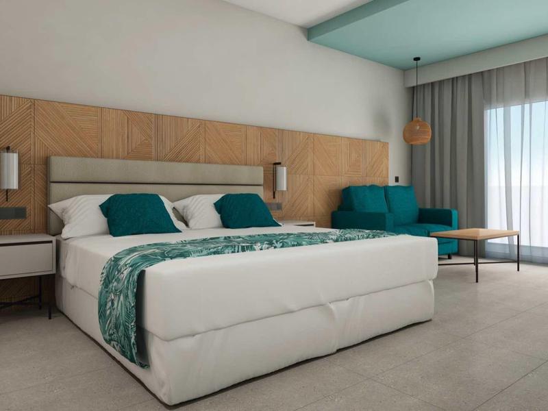 Modernes Schlafzimmer mit großem Bett, Holzkopfteil, Sofa und bodentiefen Fenstern mit Vorhängen.