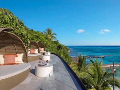 Letti rotondi moderni con cuscini su terrazza con vista sul mare e vegetazione rigogliosa.