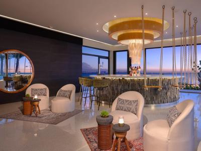 Luxuriöse Bar mit modernem Design, weißem Marmor, Rundspiegel und bequemem weißen Sitzmobiliar.