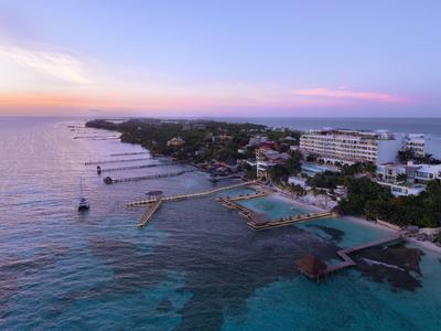 Vista aerea di un resort costiero con piscine e moli al tramonto.