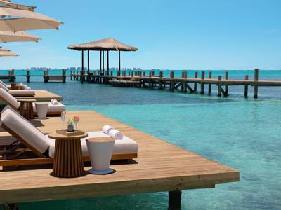 Lettini e un gazebo su un molo sopra il mare blu limpido