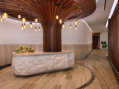 Reception di hotel moderna con colonna di legno organico e banco in marmo curvo.