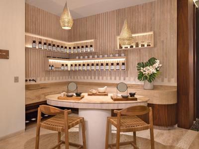 Area spa moderna con scaffali in legno, tavoli rotondi e due sedie in tonalità calde.