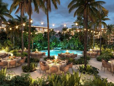 Avondterras met verlicht zwembad, palmbomen en gedekte tafels.