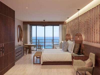 Moderne hotelkamer met tweepersoonsbed, balkon met uitzicht op zee en elegante inrichting in warme tinten.