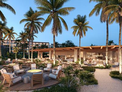 Gezellige buitenruimte van een hotel met zithoeken en palmbomen bij zonsondergang.