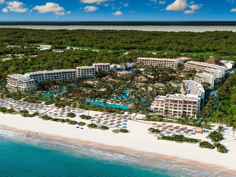 Groot strandresort met meerdere zwembaden, omgeven door weelderig groen direct aan wit zandstrand.