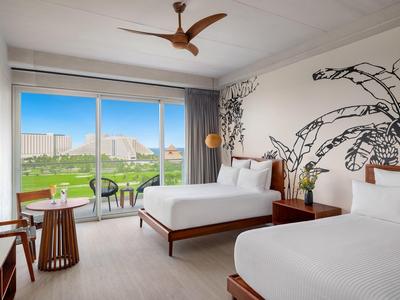 Chambre d'hôtel lumineuse avec deux lits, décoration moderne et vue sur un paysage verdoyant.