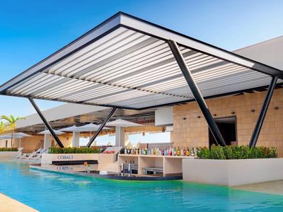 Bar extérieure moderne couverte avec bassin devant un bâtiment d'hôtel.