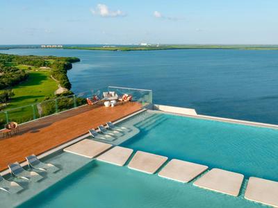 Piscina infinity con vistas al mar y paisaje verde bajo cielo despejado.