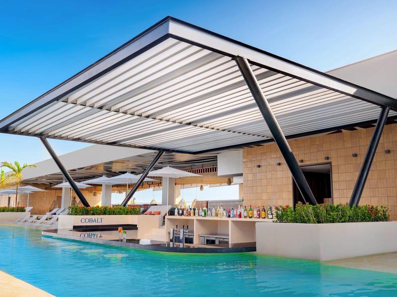 Bar extérieure moderne couverte avec bassin devant un bâtiment d'hôtel.