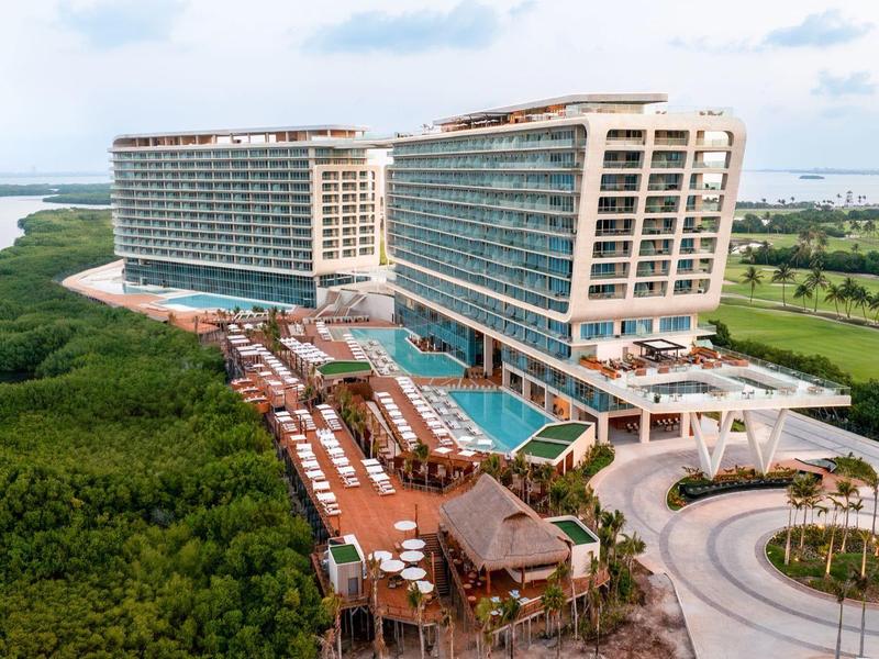 Hôtel de vacances moderne au bord de l'eau avec piscine, jardin de palmiers et accès aux mangroves.