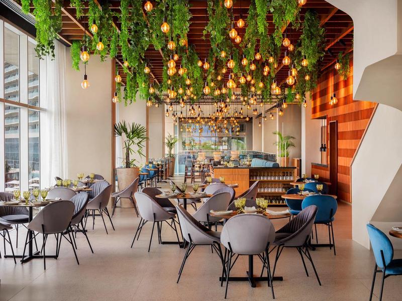 Restaurant lumineux avec des plantes vertes et des lampes suspendues jaunes au plafond