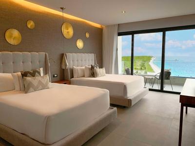 Camera d'albergo luminosa con due grandi letti e vista sul mare dalla terrazza.