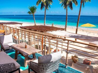 Terrazza dell'hotel con sedie e vista sulla spiaggia e palme.