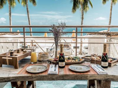 Tavola apparecchiata con vista sul mare e palme sullo sfondo.