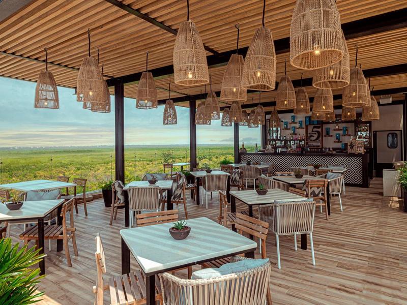 Terrazza di un ristorante con vista sul mare e arredamento in legno chiaro.