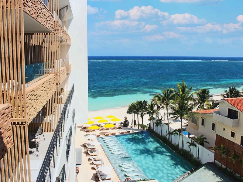 Piscina con lettini e vista sul mare turchese e cielo azzurro.